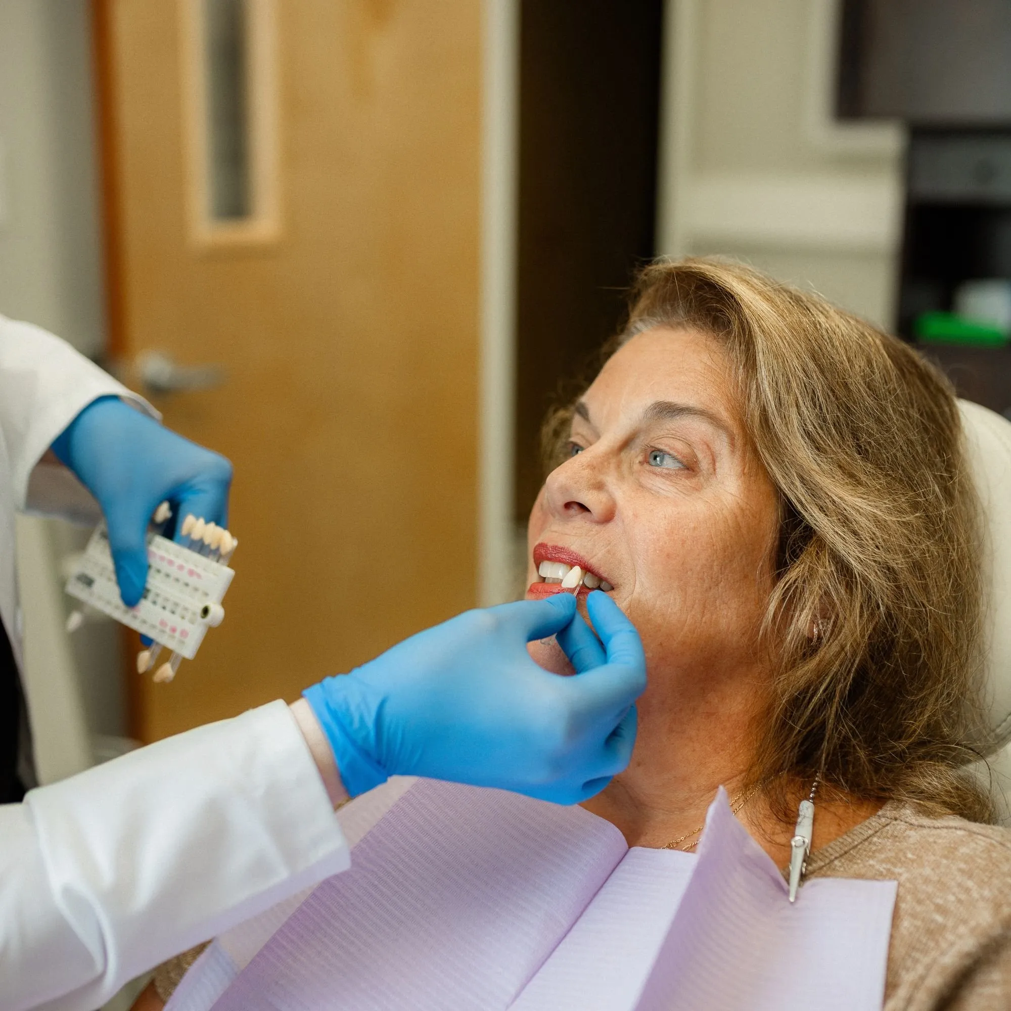 Dentist matching a tooth shade guide to a patient’s smile in Leesburg, Florida